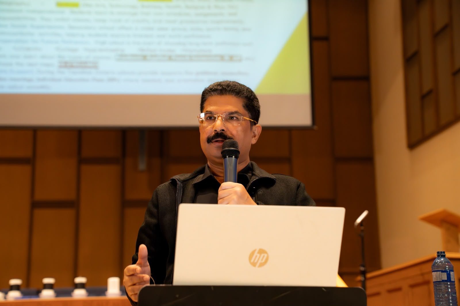 Bensy Mathew speaking at a community education conference